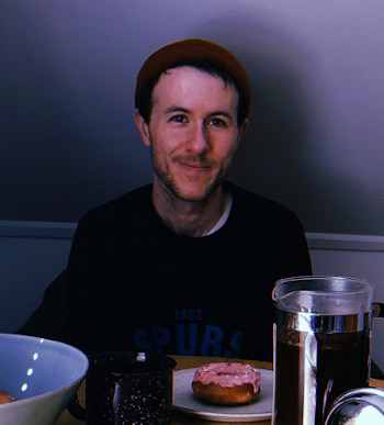 Lew sitting at the kitchen table with coffee and a donut.
